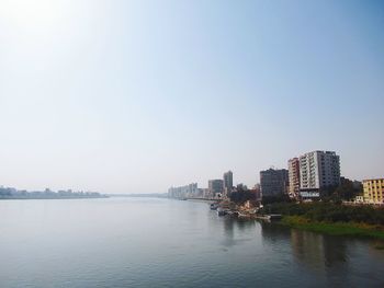 Scenic view of river by buildings against clear sky