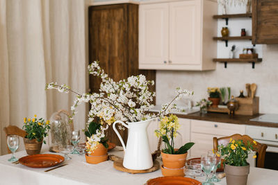 A bouquet of spring white flowers on branches in a vase on the kitchen table. scandinavian style