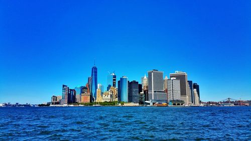 View of cityscape in front of sea against clear sky