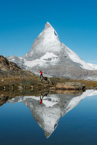 Scenic view of lake by mountain against clear blue sky