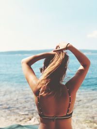 Rear view of woman standing at beach against sky