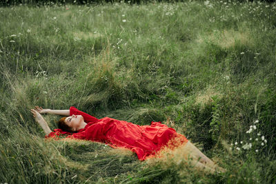 Rear view of woman lying on grassy field