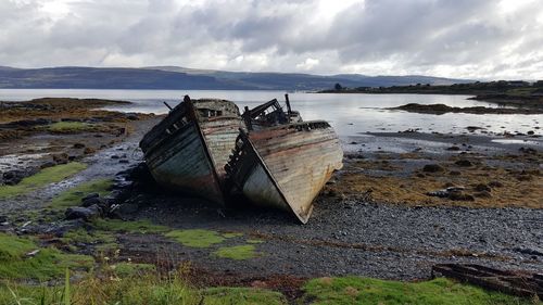 Abandoned boat on beach against sky