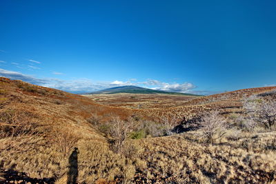 Scenic view of mountains against blue sky