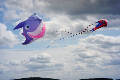 Low angle view of kites flying against sky