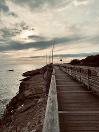 Pier over sea against sky during sunset