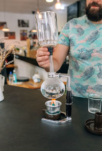 Midsection of woman holding wineglass on table
