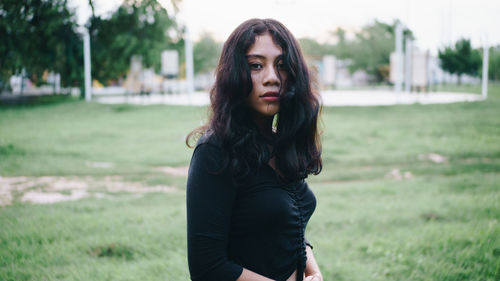 Portrait of young woman standing on field