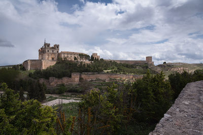 Panoramic view of the monastery, the castle and the walls of ucles against a cloudy sky, cuenca