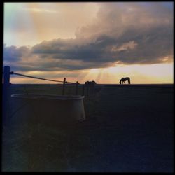 Scenic view of sea against cloudy sky at sunset