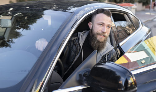 Bearded man disembarking from car