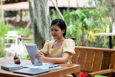 Young woman using mobile phone while sitting on table