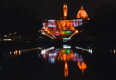 Illuminated buildings by river at night