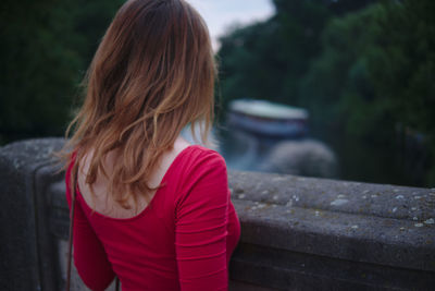 Rear view of woman standing at retaining wall