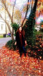 Portrait of smiling young woman standing in park during autumn