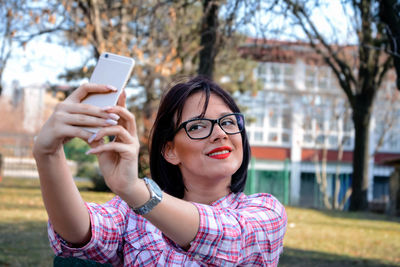 Woman taking selfie from mobile phone against trees at park
