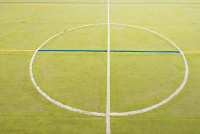 Circle in middle of court. handball playground, light green surface and white blue bounds lines.