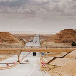 Empty straight road in the desert against sky