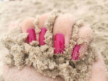 Close-up of hand holding ice cream on sand