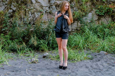 Young woman standing at beach against rock formation