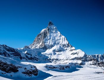 Scenic view of snowcapped mountains against clear blue sky