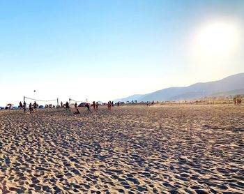 Group of people on beach against clear sky