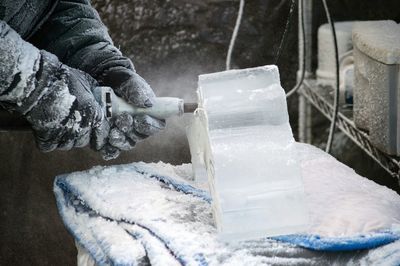 Cropped image of craftsperson shaping ice during winter