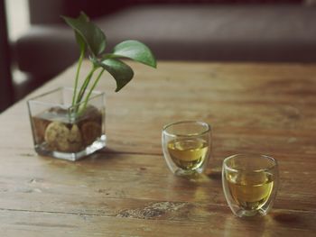 Tea in glass by leaves on wooden table