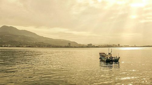 Boats in sea at sunset