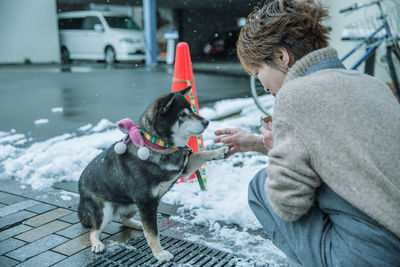 Mature woman playing with dog on street during winter