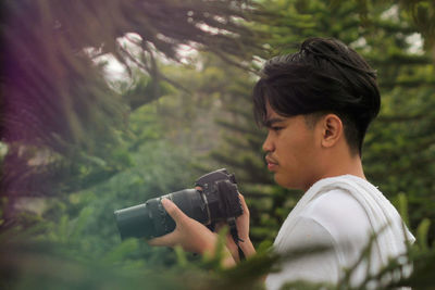 Side view of young man photographing camera