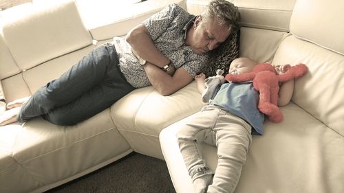 High angle view of grandfather and grandson sleeping on sofa at home