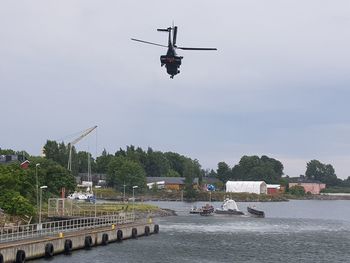 Helicopter flying over river against sky