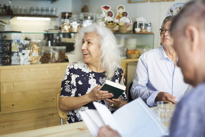 Senior man and woman with books sitting at table in coffee shop