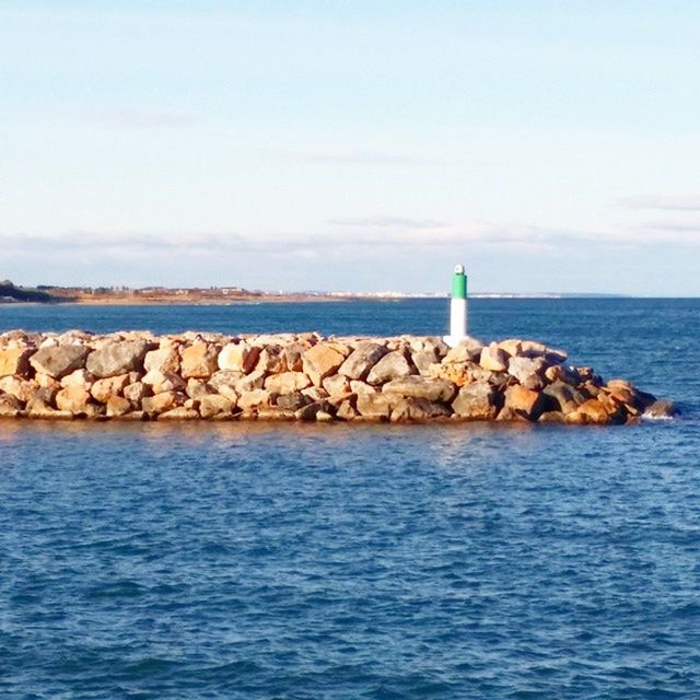 sea, water, horizon over water, sky, tranquil scene, tranquility, scenics, lighthouse, rock - object, beauty in nature, waterfront, nature, blue, guidance, built structure, rippled, protection, idyllic, day, cloud