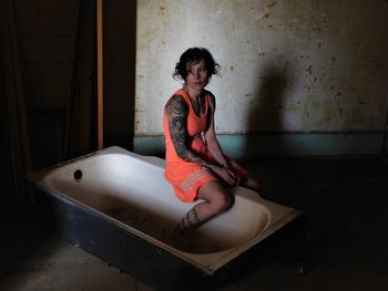 Woman sitting on bathtub at abandoned building