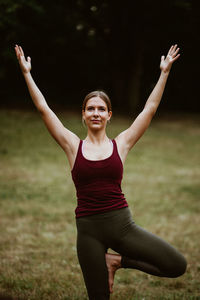 Young woman with arms raised on field