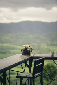 Chair on table by railing against sky