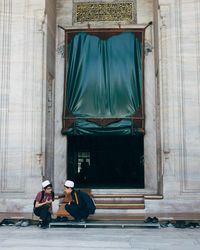 Rear view of couple sitting on entrance of building