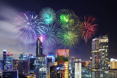 Firework display over illuminated buildings in city at night