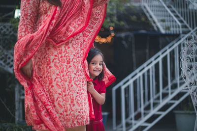 Portrait of smiling girl standing with mother against steps