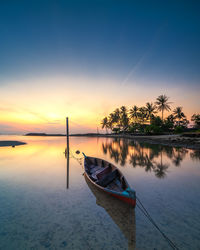 Boat moored in lake against sky during sunset