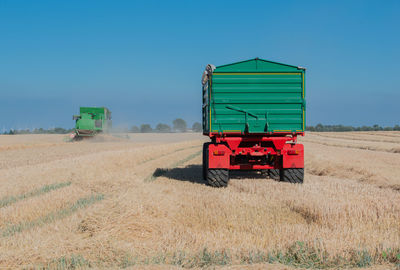 Agricultural machinery on field against clear blue sky