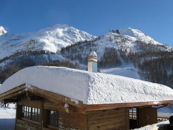 House on snow covered mountain against sky