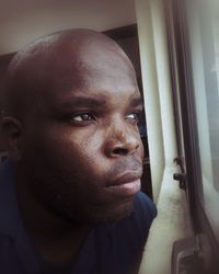 Close-up of thoughtful man looking through window at home