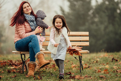 Full length of women sitting on seat in field