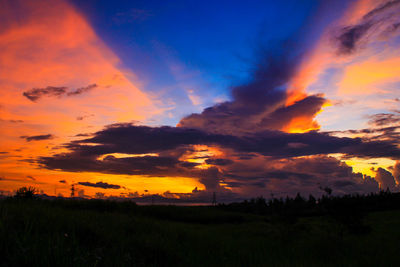 Scenic view of dramatic sky over field during sunset