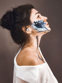 Close-up of woman with face paint against wall