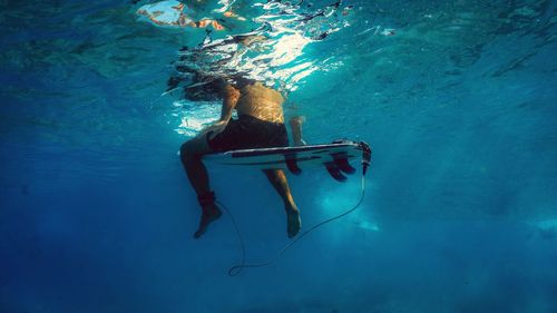 Low section of shirtless man surfing undersea