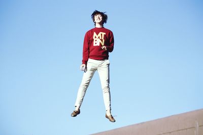 Low angle portrait of man against clear blue sky